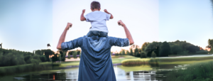 A son riding the shoulders of his dad.